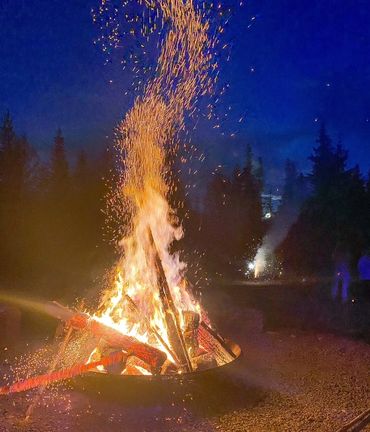 A large campfire blazing at night with sparks flying upward.