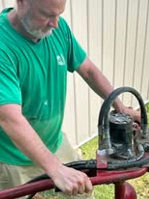 Fence repair specialist Ronald Willis of Willis Outdoors LLC drilling post hole with an auge