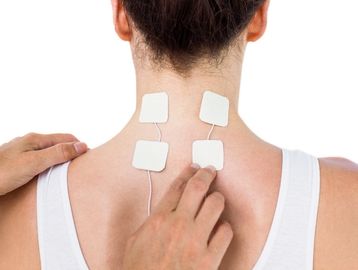 Muscle stimulation electrotherapy pads on patient's  back. 