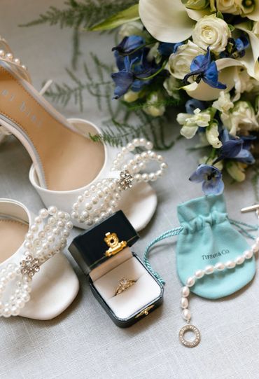 Elegant bridal accessories with pearl-embellished shoes, engagement ring, and Tiffany & Co. jewelry.