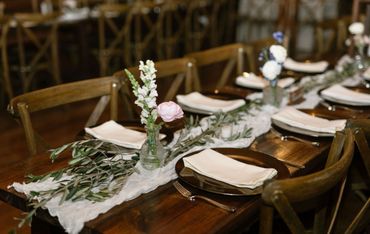 Elegant table setting with floral centerpieces and neutral-toned napkins on wooden tables.