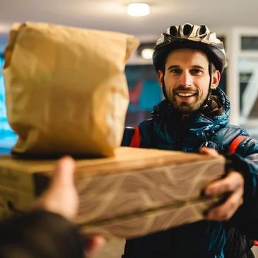A delivery person hands over packages with a smile.