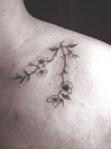 Delicate cherry blossom tattoo on shoulder.