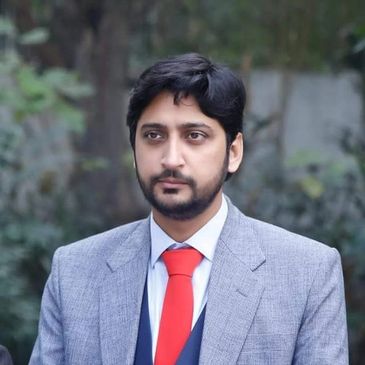 Man wearing gray suit and red tie outdoors.