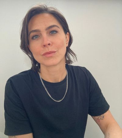 Woman with short hair wearing a black shirt and silver chain necklace.