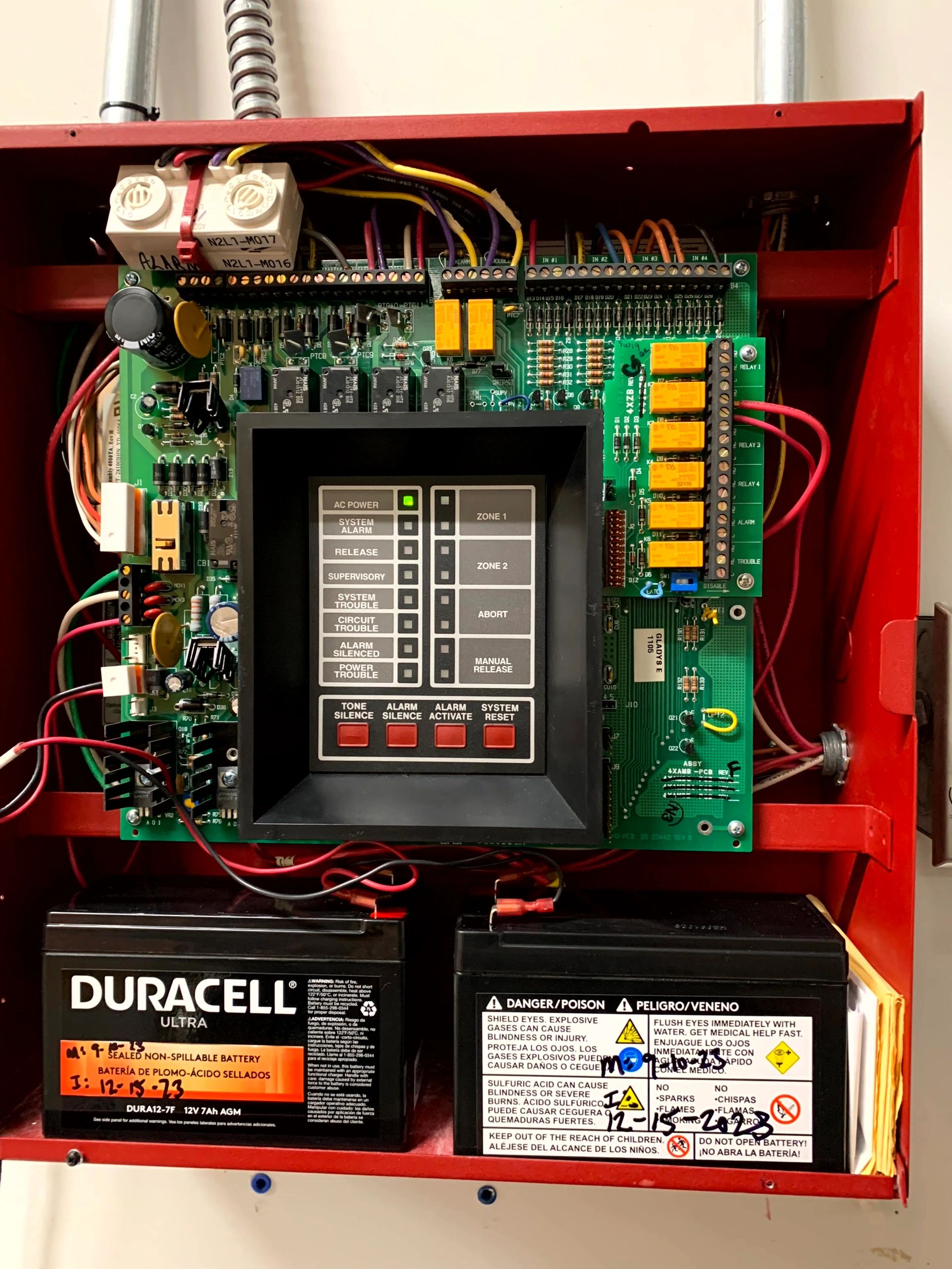 Fire alarm control panel with batteries and control buttons.