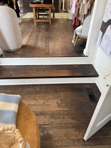 Interior of a clothing store with wooden floors and a step.