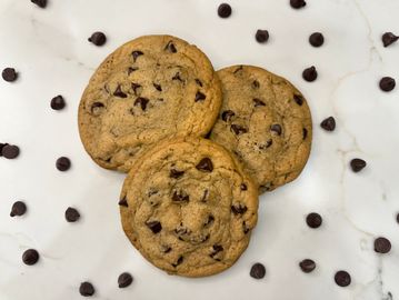 Three chocolate chip cookies with scattered chips.