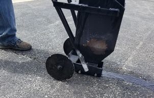 Showing Hot rubber application to a crack in a parking lot.