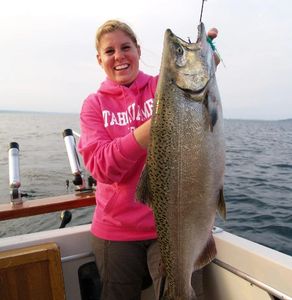 Woman proudly holding a large fish on a boat.