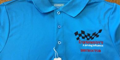 Trackmasters logo on a blue polo shirt