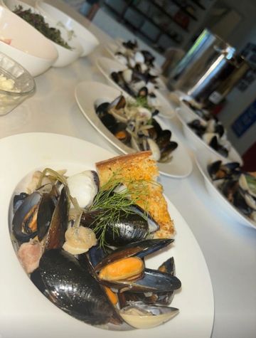 Clams and mussels with toast on white plates.