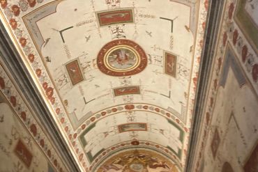 Ornate ceiling with intricate frescoes and classical motifs in a historic building.