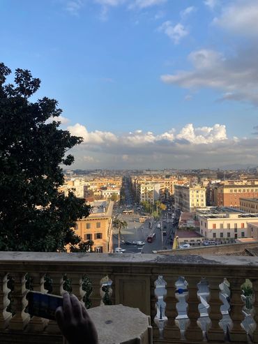 View of a cityscape with a long street lined by buildings under a bright sky.