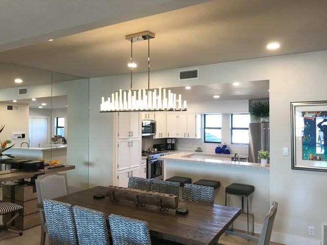 Recessed lighting and chandelier in remodeled home kitchen and dining area.