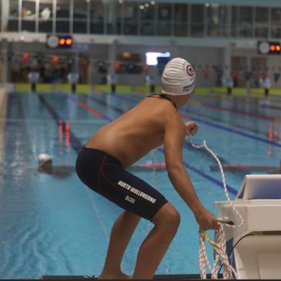 Young swimmer ready to dive at indoor pool.