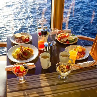 Breakfast spread on a table by a window overlooking the ocean.