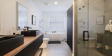 Modern bathroom with black fixtures, wood countertop, and a freestanding bathtub.