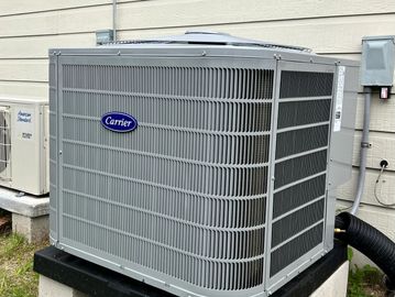A Carrier brand outdoor air conditioning unit installed beside a house.