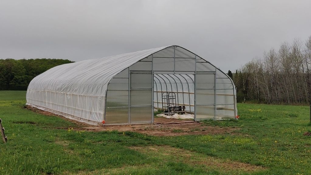 A greenhouse in a grassy field.