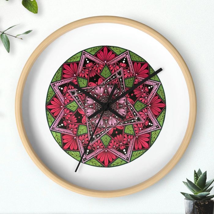 A clock with a vibrant pink & green mandala design with black hour and minute hands.