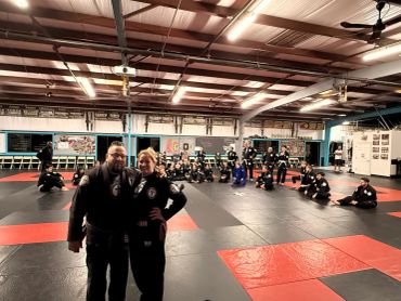 A group martial arts class posing on mats in a gym.