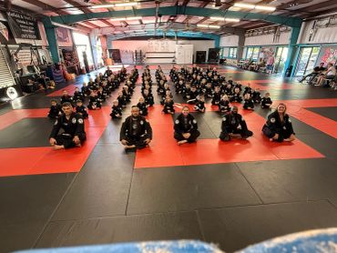 Martial arts group photo with instructors and students seated on mats.