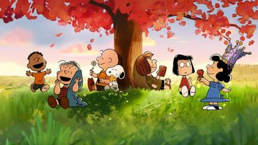 Peanuts gang enjoying a peaceful moment under a vibrant autumn tree.