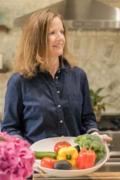 Woman holding a bowl of fresh vegetables.
