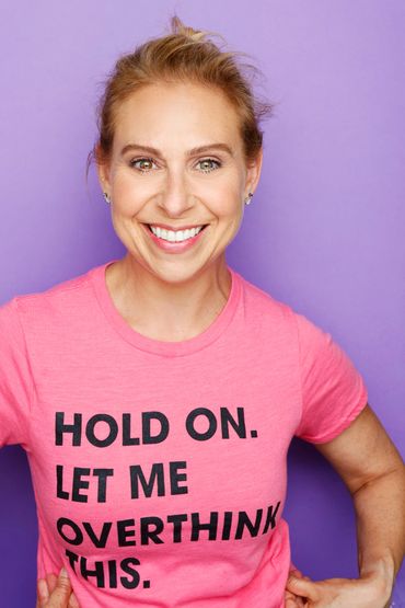 Smiling woman in pink shirt with humorous text against purple background.