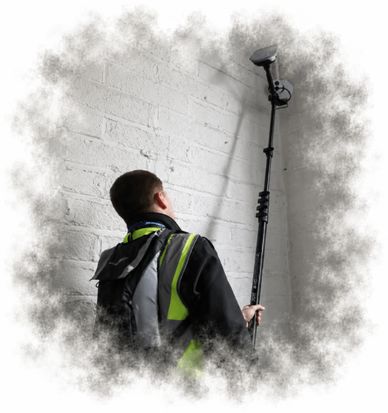 Worker using a surveying tool against a white brick wall.