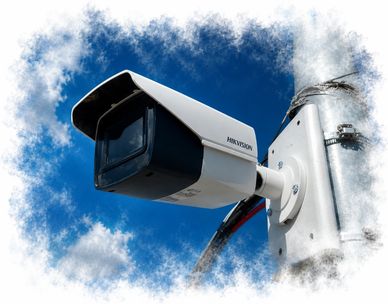 White Hikvision security camera mounted outdoors against a blue sky.