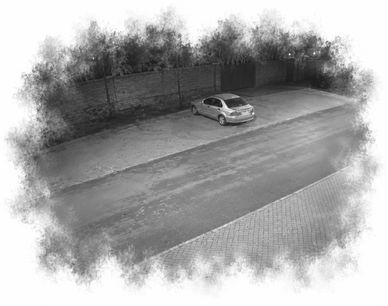 A silver car parked near a brick wall on a quiet street at night.