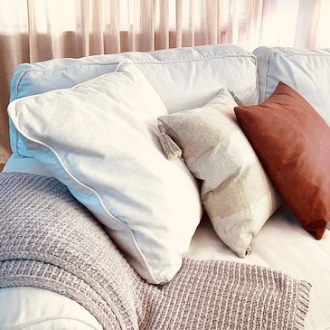 neutral pillows on a beige couch with cozy blanket