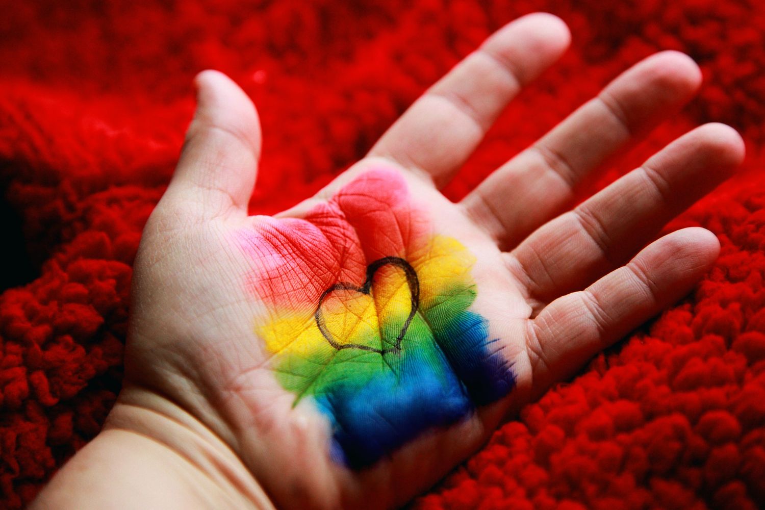 Rainbow heart in open helping hand
