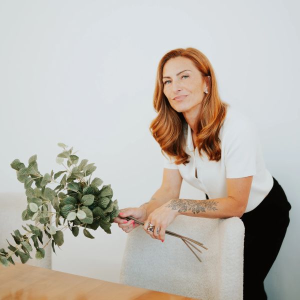Femme souriante tenant un bouquet de feuilles vertes.