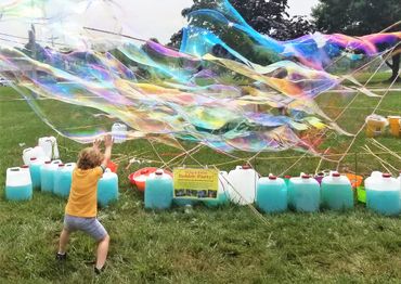 Boys and girls love to challenge giant bubbles that Grandpop Bubbles makes.