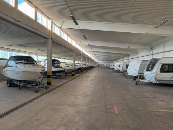 Lagerhalle mit geparkten Booten und Wohnwagen.
