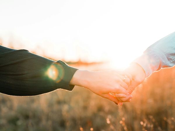 Two hands holding in sunlight.