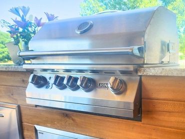 Close up view from covered porch of custom built-in grill - cedar wood & granite countertop by MDR.