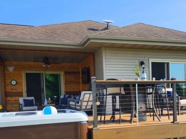View from backyard of newly expanded outdoor kitchen, hot tub, & deck in Wisconsin by MDR Design Co.