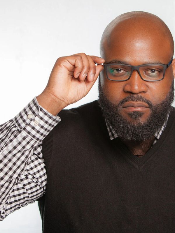 Man adjusting his glasses and looking confidently.