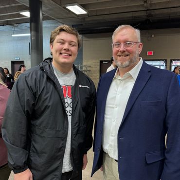 Two men smiling and posing indoors at an event.