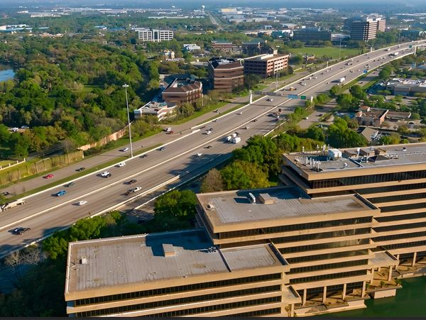 Aerial view of highway with office buildings and green trees in a suburban cityscape