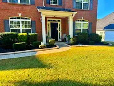 Front view of house showing lawn with black mulch bed and trimmed bushes