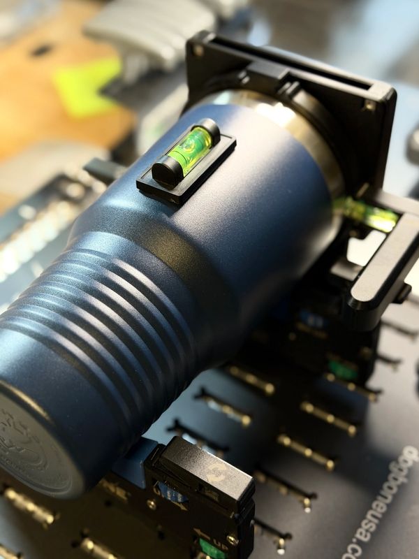 Close-up of a blue metal tool with a built-in bubble level on a black surface.