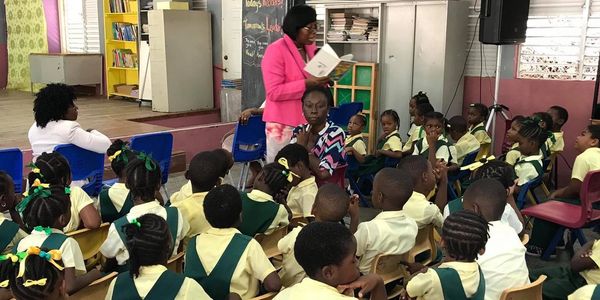 Volunteer reading to students during a Read Across Grenada, Carriacou & Petite Martinique Day event
