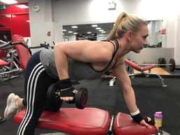 Woman performing single-arm dumbbell row in a gym.