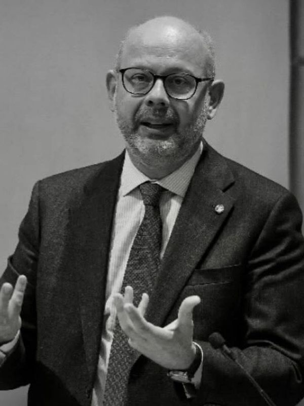 A man in a suit speaking and gesturing with his hands.