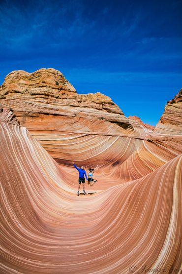 The iconic Wave with beautiful swirling sandstone and happy hikers jumping for joy.